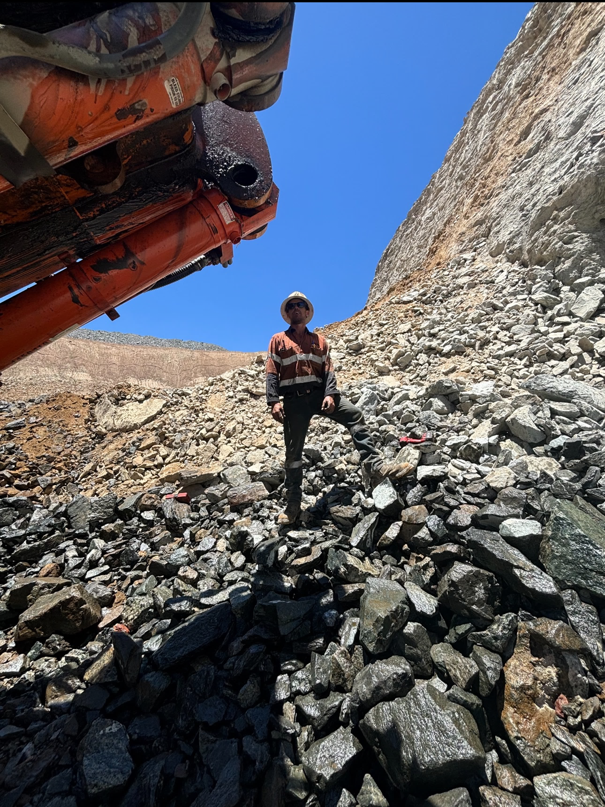 Mechanic under excavator bucket